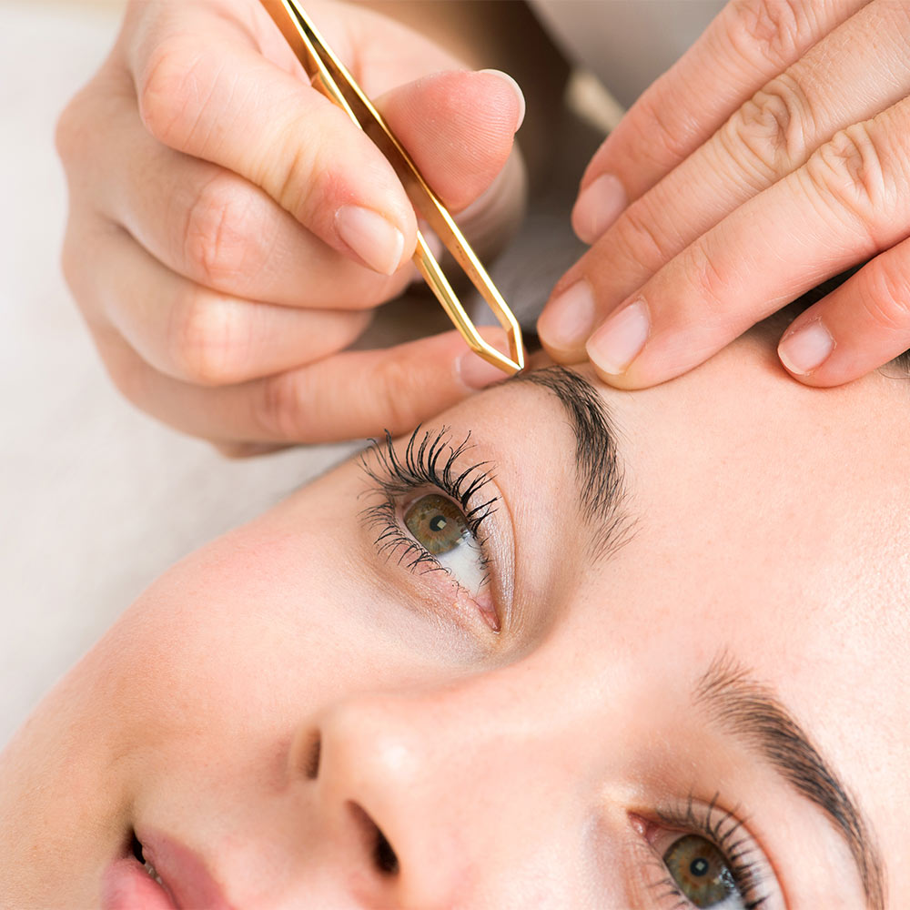 Kosmetikstudio Augenbrauen werden von Hand mit Pinzette bei jung