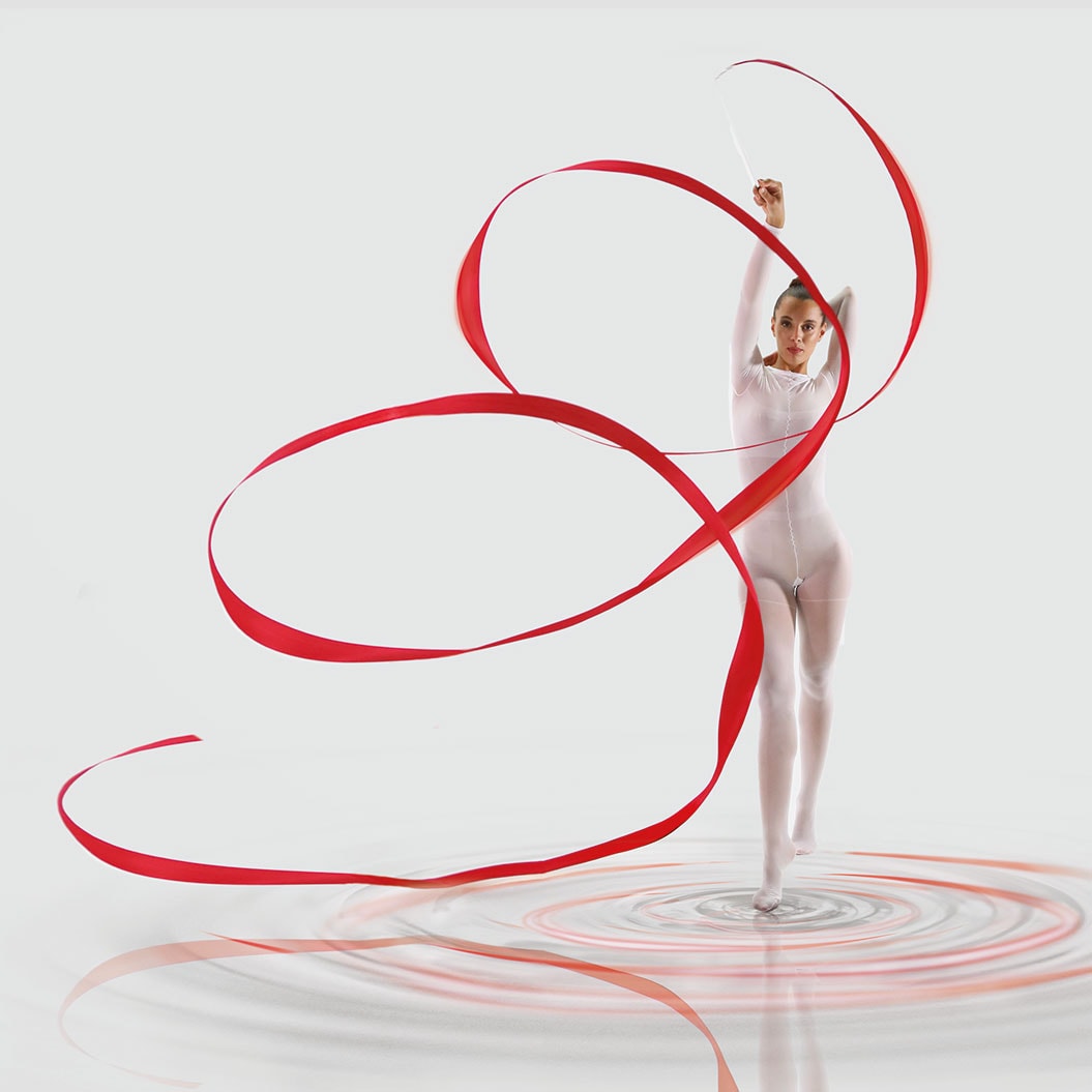 Rhythmische Sportgymnastin mit stilvollem, rotem Band und konzentriertem Ausdruck in weißem Anzug.